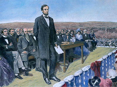 A historical illustration depicts a man standing and speaking with a paper in hand, in front of a seated group outdoors. The table nearby holds books. The area is decorated with a banner of stars. A crowd is gathered in the background.
